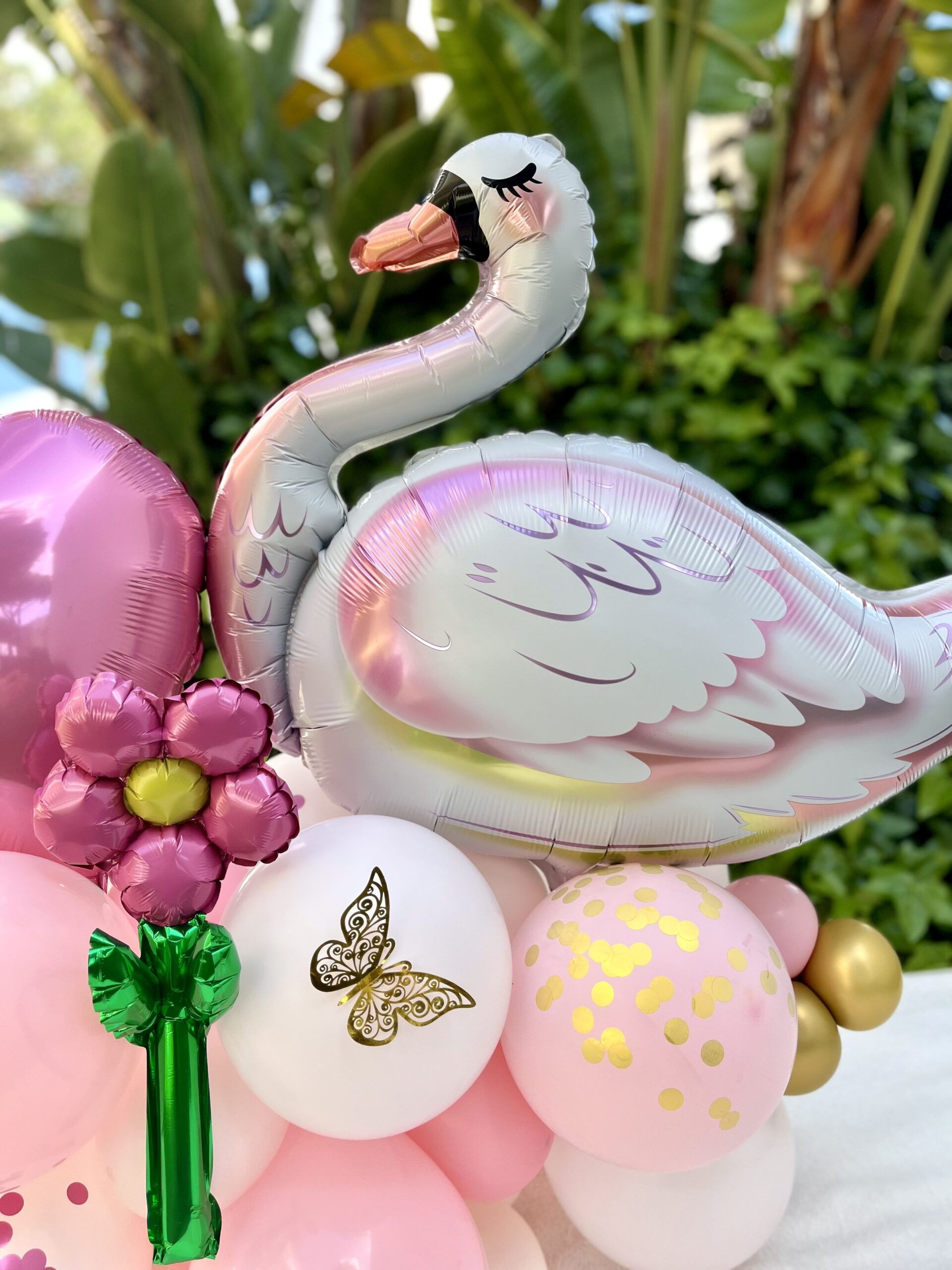 Arranjo de balões em tons rosa com cisne e flores para festa